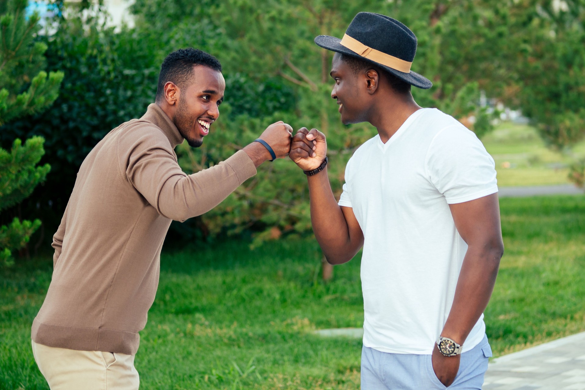 two black men in stylish suits meeting in a summer park. African-Americans friends hispanic businessman greeting each other teamwork outdoors