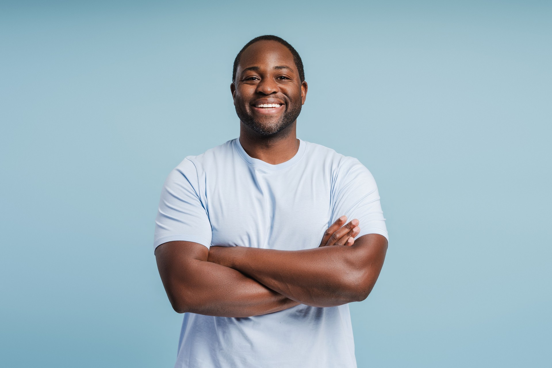 Happy young African American man posing with arms crossed in studio